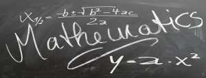 Descrição de imagem: Imagem de um quadro negro contendo a palavra &quot;mathematics&quot; (matemática em inglês), uma função matemática e a fórmula de Bhaskara escritos em giz branco.