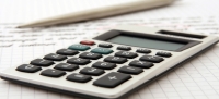 Imagem de uma calculadora sobre um papel rascunhado em lápis.