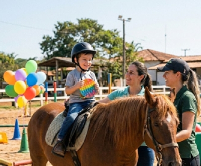 Criança em sessão de equoterapia acompanhada por duas monitoras
